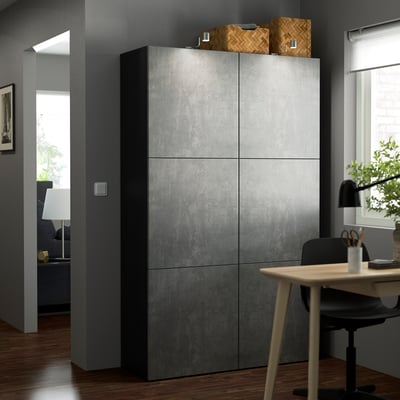 Large grey BESTÅ cabinet, modern minimalist design, tall with flat doors, standing near a desk and window.