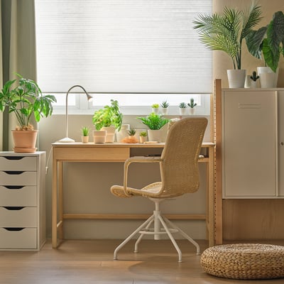 Natural bamboo desk, woven chair, plants, adjustable. Hand-woven seat, single drawer, minimalist. Blinds, wood floor, stool - cosy, nature-inspired.
