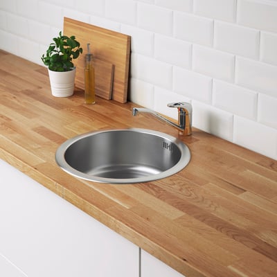 Stainless steel kitchen sink in wooden counter with chrome tap.