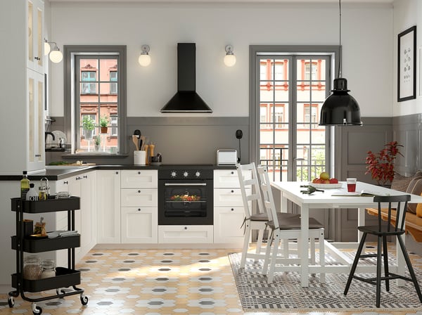 Modern kitchen with white ENKÖPING cabinets, black fixtures, and patterned floor tiles. Large windows let in natural light.