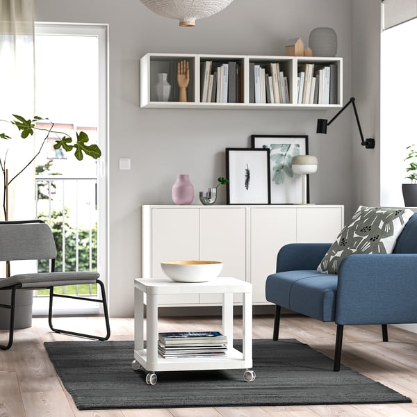 Modern living room with white table, blue chairs, grey rug, and greenery.