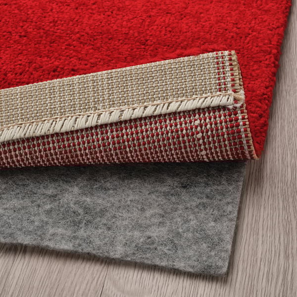 Three layered rugs: red striped, beige, grey felt. Illustrates rugs cosy, non-slip design.