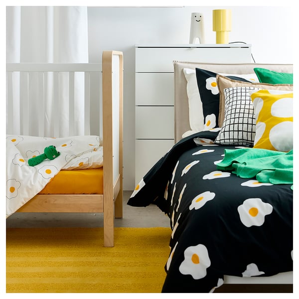 Kids room with bunk beds: one yellow, one multi-color. White dresser with lamp and robot.