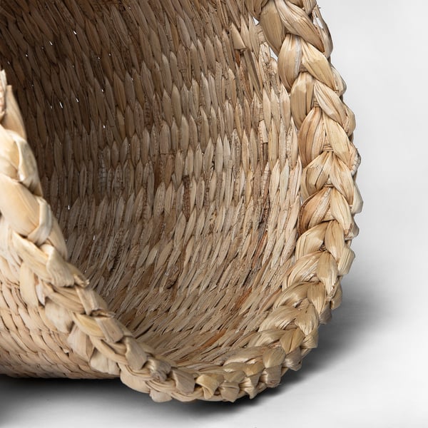 Hand-braided lampshade with natural banana fibres, emitting warm light through small openings.