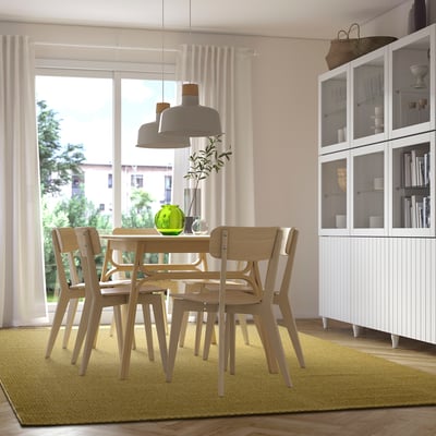 Modern dining room with light wooden table, chairs, grey pendant lamp, and green MORUM rug.