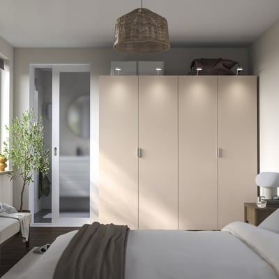 Modern bedroom with large PAX wardrobe, soft lighting, hanging lamp, plant, and bed with table lamp.