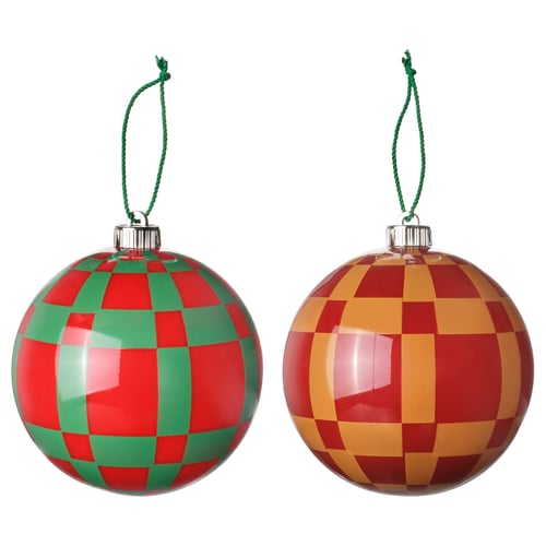 Two round, colourful christmas ornaments, one red and green chequered, the other red and yellow, with green hangers.