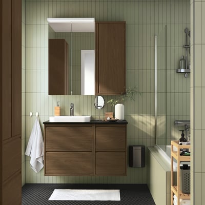 Ein modernes Badezimmer mit ÄNGSJÖN-Waschtisch, Waschbecken, Spiegel, Glasdusche, Hängetuch und Lattenrost - grüne Fliesen.