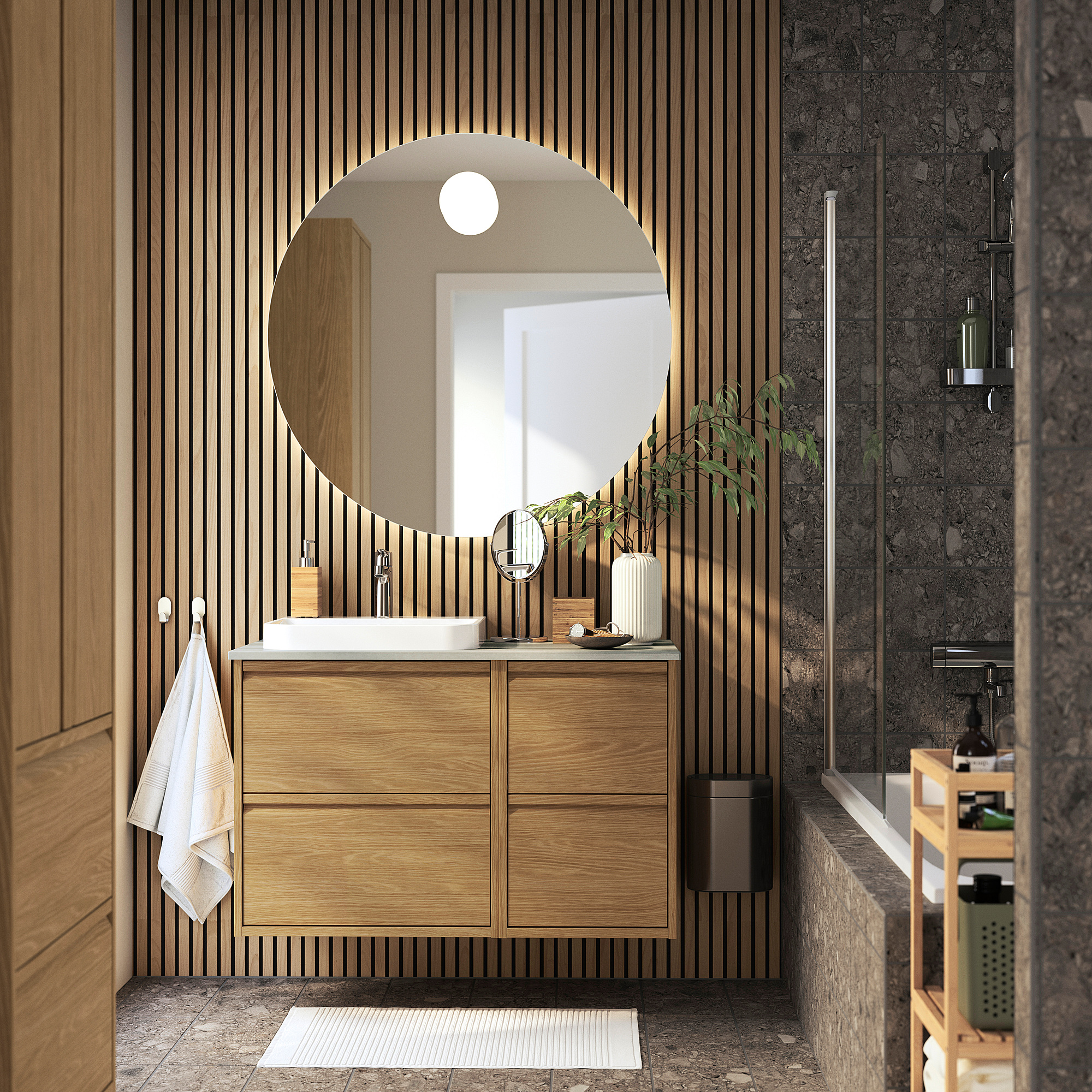 ÄNGSJÖN Badezimmer: Waschtisch aus Eiche, Marmorwaschbecken, großer Spiegel, Glasdusche, Granitwand, warmer moderner Stil.