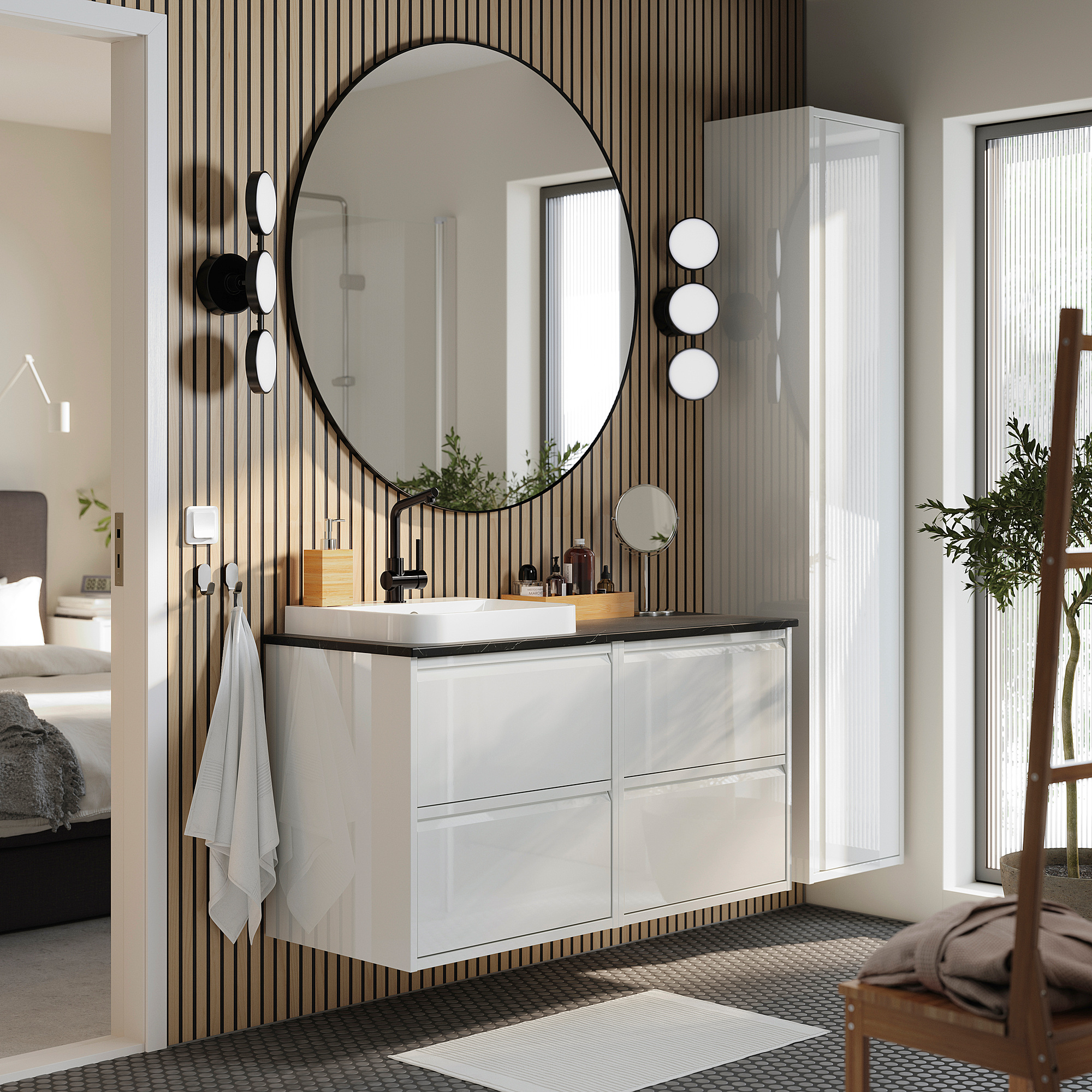 Dieses moderne Badezimmer ist der weiße Waschtisch ÄNGSJÖN mit Marmorwaschbecken, einem großen runden Spiegel und eleganten schwarzen Akzenten, die ein minimalistisches Design schaffen.