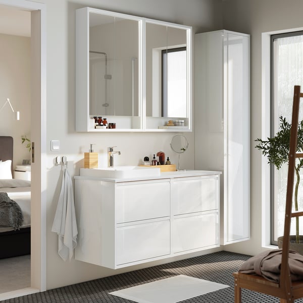 Ein modernes weißes Badezimmer mit ÄNGSJÖN-Schränken, Hängeschränken, Arbeitsplatte, Waschbecken, Hochglanz-Oberfläche und einem kleinen Stuhl.