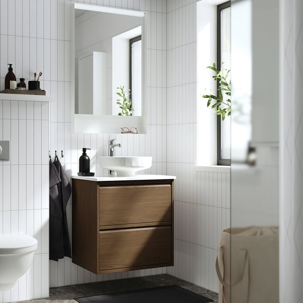 Modernes Badezimmer: eleganter Schrank aus Nussbaumholz, weißes Waschbecken, großer Spiegel, Pflanzen.