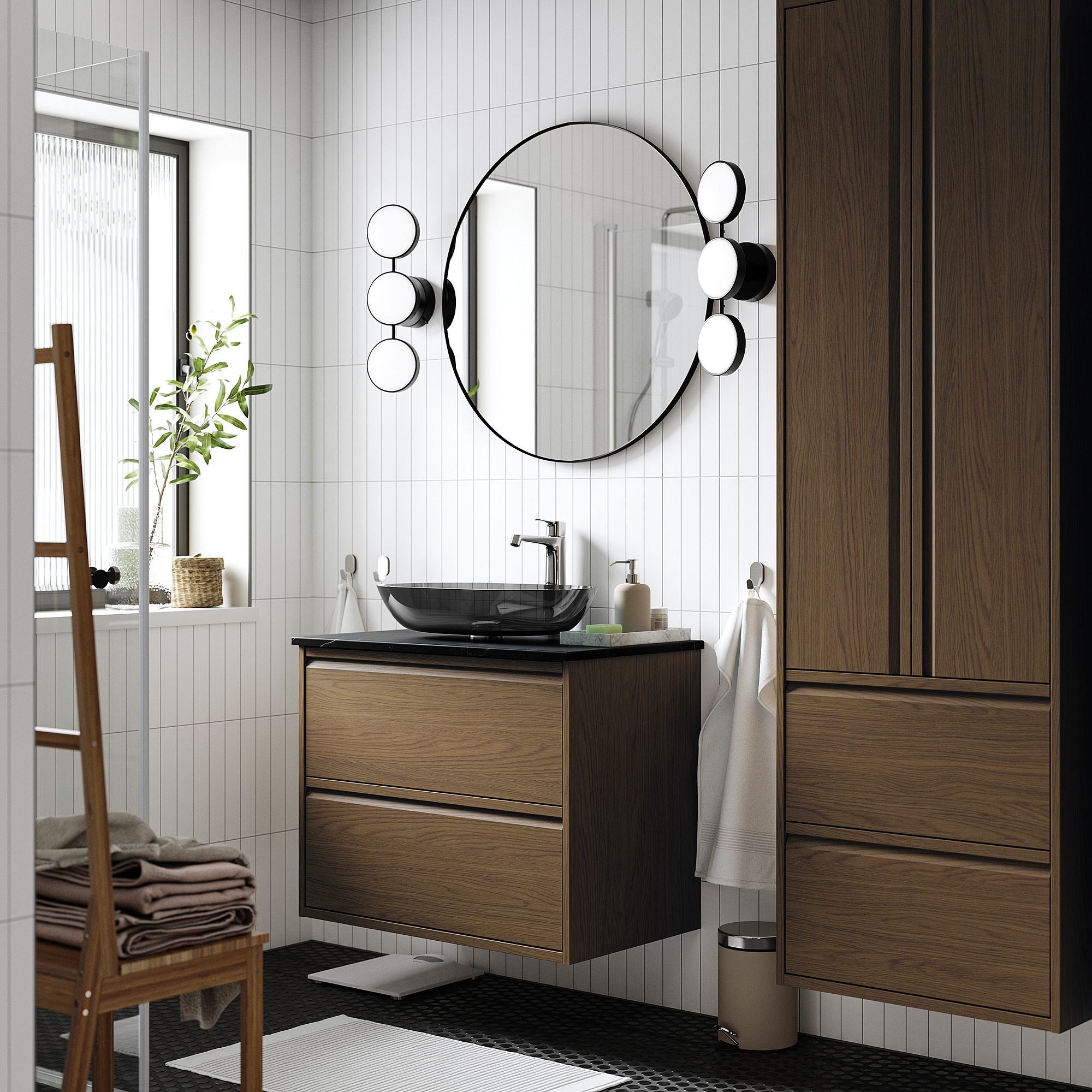 Moderner Badezimmerschrank aus dunklem Holz mit Glaswaschbecken, rundem Spiegel und kugelförmigen Leuchten, die mit glänzenden weißen Fliesen kontrastieren.
