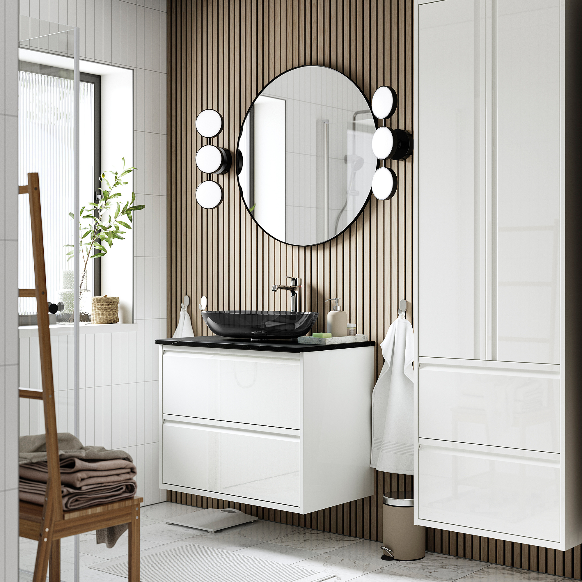 Modernes Badezimmer ÄNGSJÖN weißer Waschtisch mit Glaswaschbecken, rundem Spiegel und Holzstuhl mit Handtüchern.