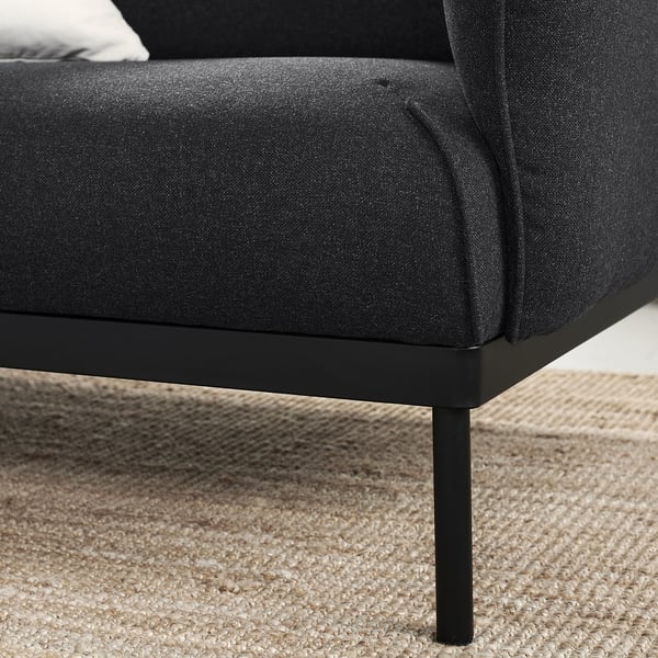 Modernes schwarzes Stoffsofa auf dunklen Metallbeinen.