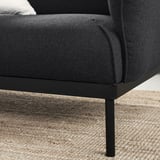 Modernes schwarzes Stoffsofa auf dunklen Metallbeinen.