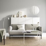 Modernes, minimalistisches Wohnzimmer mit grauem ÄPPLARYD-Sofa, weißen Akzenten und eleganten Möbeln.
