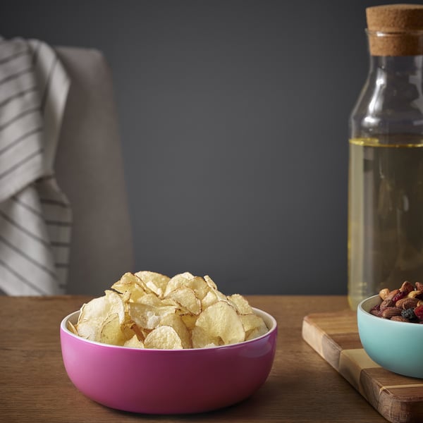 Leuchtend rosa ÅKERHALLON-Schale aus Bambus für Snacks. Kleiner als nahegelegenes Glas und Schüssel, auf Holztisch.