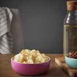 Leuchtend rosa ÅKERHALLON-Schale aus Bambus für Snacks. Kleiner als nahegelegenes Glas und Schüssel, auf Holztisch.