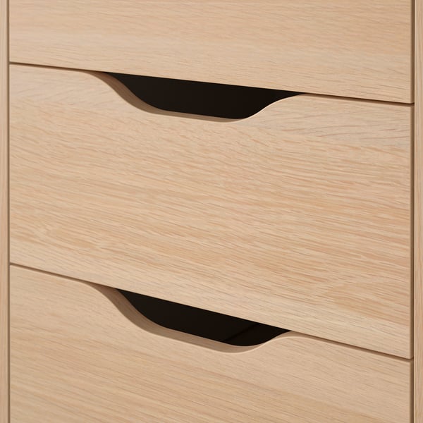 Leichter Schreibtisch aus Holz mit drei Schubladen, jede mit schlanken ausgeschnittenen Griffen, die in einer sauberen vertikalen Linie angeordnet sind.