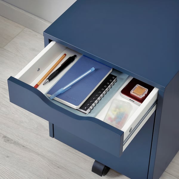Blauer ALEX-Schubladenschrank mit Notizbüchern, Stiften und kleinen Aufbewahrungsgegenständen im Inneren, ideal für die Organisation auf dem Schreibtisch.