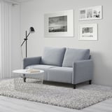 Graues ANGERSBY-Sofa mit minimalistischem Dekor, zotteligem Teppich, Couchtisch und Stehlampe.