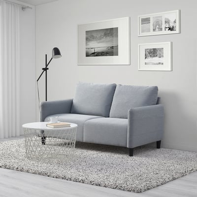 Graues ANGERSBY-Sofa mit minimalistischem Dekor, zotteligem Teppich, Couchtisch und Stehlampe.