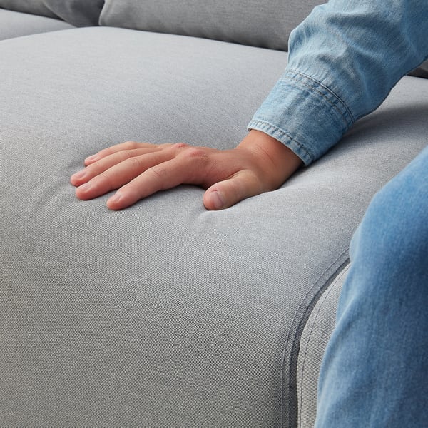 Hand auf hellgrauem ANGERSBY Sofa; Weiches, strukturiertes Gewebe mit Stauraum an den Armen.