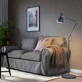 Graue ARÖD Stehleuchte neben einem grauen Sofa, hoch und verstellbar, sticht hervor.
