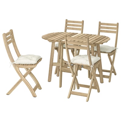 ASKHOLMEN Outdoor-Set: 4 hellbraune Klappstühle aus Holz mit weißen Kissen und einem passenden Tisch.