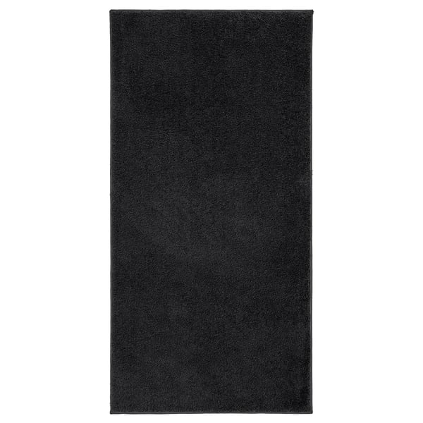 Eine schwarze, rechteckige BACKMÅRA-Badematte aus recyceltem Polyester mit weichem Flor und Latexrücken.