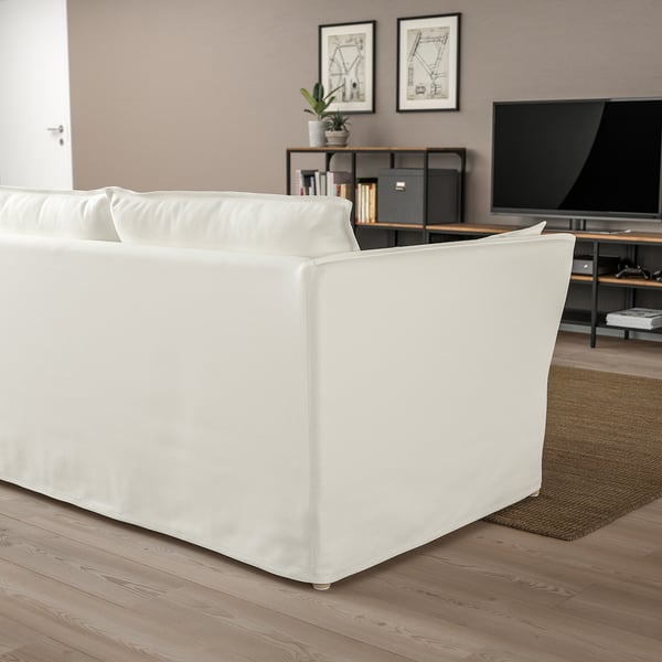 Modernes Wohnzimmer: weißes BACKSÄLEN Sofa, groß auf hellem Holzboden, mit TV und Regalen dahinter.