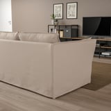 Modernes, minimalistisches Wohnzimmer mit großem beigem BACKSÄLEN-Sofa, Holzboden, TV und dekorativem Teppich.