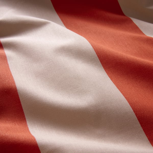 Gestreifte Bettdecke aus orangefarbener und weißer Baumwolle, weiche Textur.