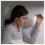 Frau entspannt sich auf dem Bett mit Kissen.