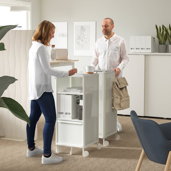 Frau und Mann diskutieren bei Kaffeetasse über Arbeit in der Nähe der mobilen BEKANT-Einheit.