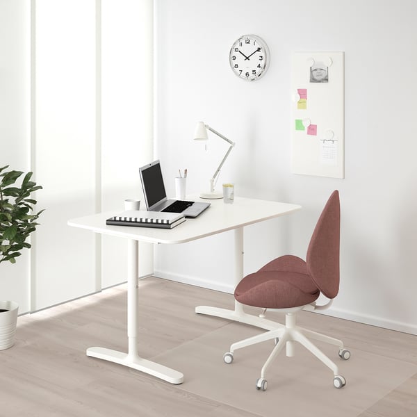 BEKANT weißer Schreibtisch mit rotem Stuhl, schlankem Design, geräumiger Platte, verstellbaren Beinen, mit Lampe, Laptop, Pflanze und Uhr.