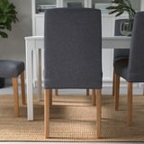 Moderne Essgarnitur mit grauen gepolsterten Stühlen, Holzbeinen, auf Naturteppich.