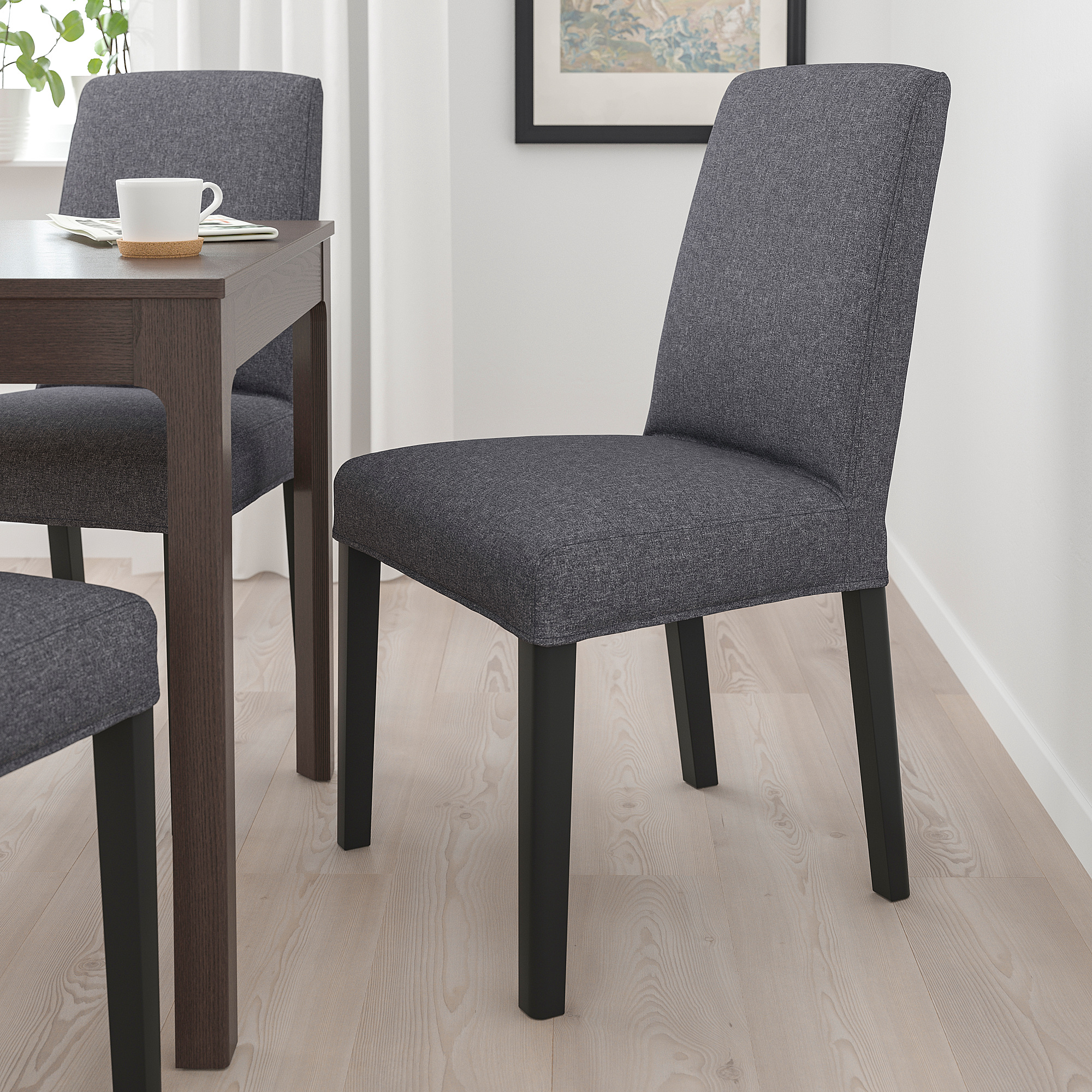 Moderner Esszimmerstuhl aus grauem Stoff, hoch und schlank. Passt unter den Tisch, mit gepolstertem Sitz und gepolsterter Rückenlehne.