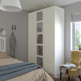 Großer cremefarbener BERGSBO-Kleiderschrank mit Spiegel im Schlafzimmer, neben Bett und Stuhl.