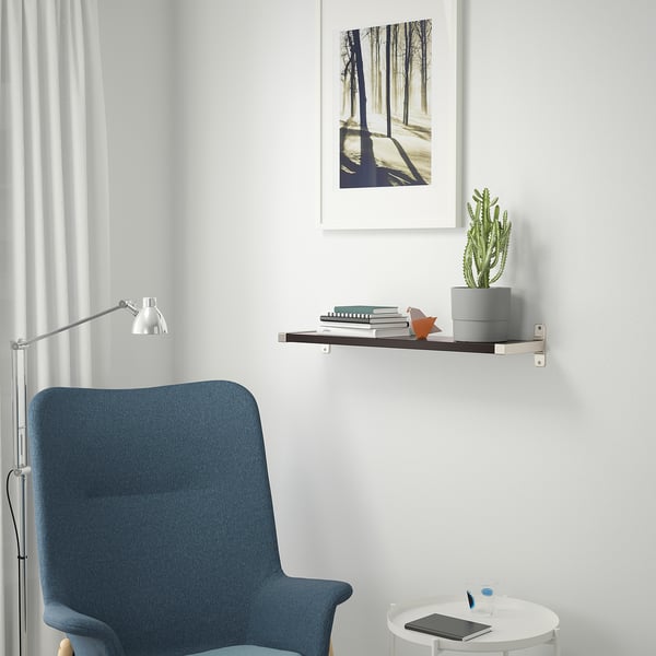 Eine minimalistische Leseecke mit Regal, Pflanze, Büchern, Figur, Stuhl, Lampe und Tisch mit Tablet.