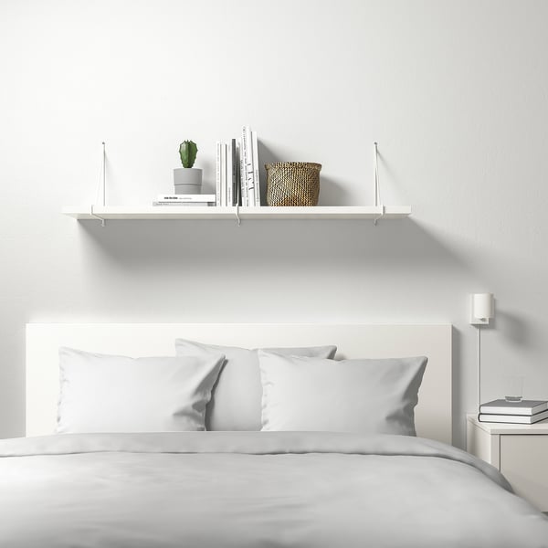 Minimalistisches Schlafzimmer mit BERGSHULT Wandregal für Bücher, Pflanzen und Korb. Saubere weiße Linien.