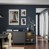 Modernes Esszimmer mit dunkelgrauem BESTÅ-Stauraum, weiß gerahmter Kunst und Holztisch.