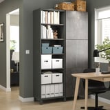 Modernes Home Office mit schwarzem BESTÅ-Bücherregal mit Aufbewahrungsboxen und Büchern, neben einem Holzschreibtisch mit Stuhl.