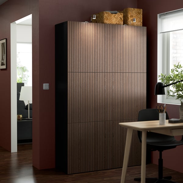 Modernes Zimmer mit großem, hohem BESTÅ-Aufbewahrungsraum aus Holz. Stuhl und Schreibtisch in der Nähe.