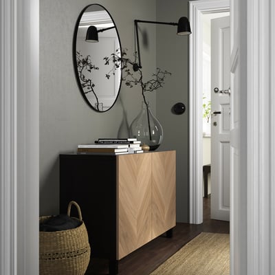 Minimalistischer Eingangsbereich mit BESTÅ Sideboard, Büchern, Vase, Korb, Spiegel, Wandleuchte.