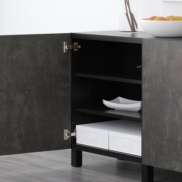 Dunkler Holzschrank mit offener Tür, der Staufächer und weiße Boxen freigibt. Modernes Design, verstellbare Regale.