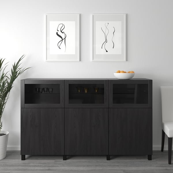 BESTÅ Sideboard mit Glastüren, Gegenständen, Kunst, Pflanze, Schale, weißem Stuhl.