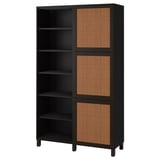 Ein IKEA BESTÅ Aufbewahrungsschrank in Schwarz mit geflochtenen Paneelen. Er verfügt über offene und geschlossene Fächer zur Aufbewahrung und Präsentation.