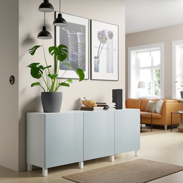Modernes Wohnzimmer mit blauem BESTÅ-Sideboard, grüner Pflanze, Büchern und orangefarbener Couch.